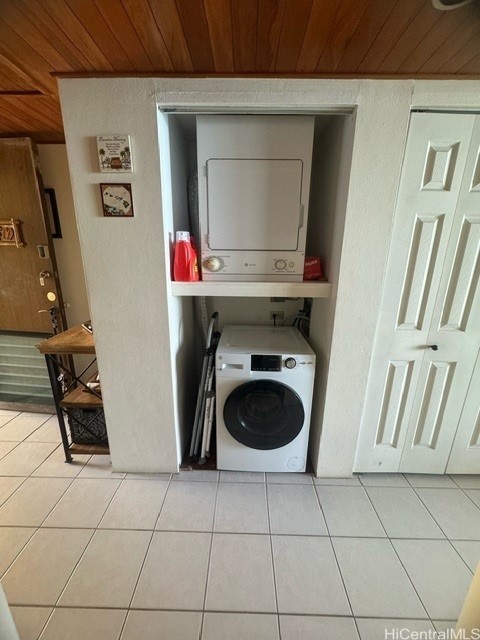 laundry room featuring stacked washing maching and dryer, wooden ceiling, and light tile patterned flooring