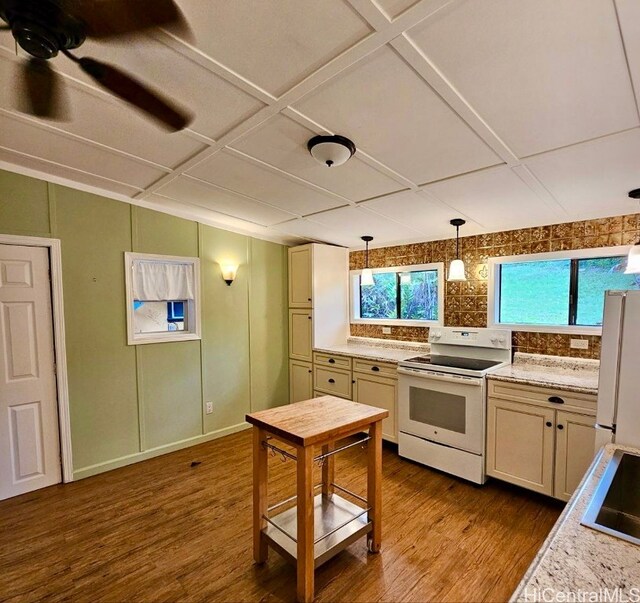 kitchen with a wealth of natural light, white appliances, decorative light fixtures, and light hardwood / wood-style floors