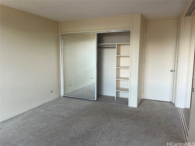 interior space featuring a textured ceiling, a closet, and dark carpet