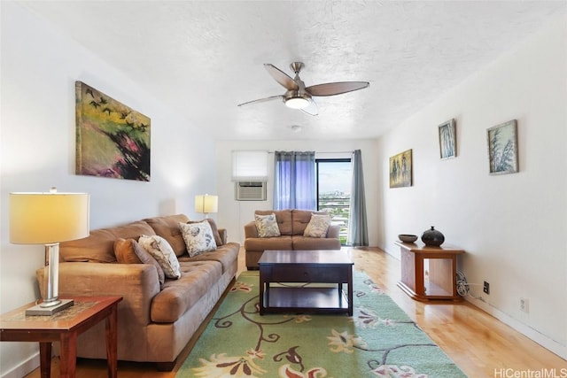 living room featuring ceiling fan, light hardwood / wood-style floors, and a textured ceiling