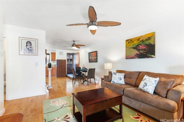 living area featuring light wood finished floors, ceiling fan, and baseboards