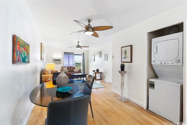 living room with light wood-type flooring, ceiling fan, and stacked washer and clothes dryer