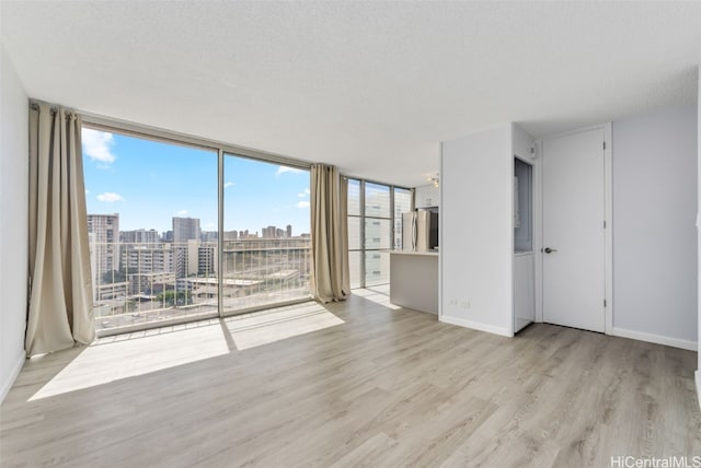 spare room featuring a textured ceiling and light hardwood / wood-style floors