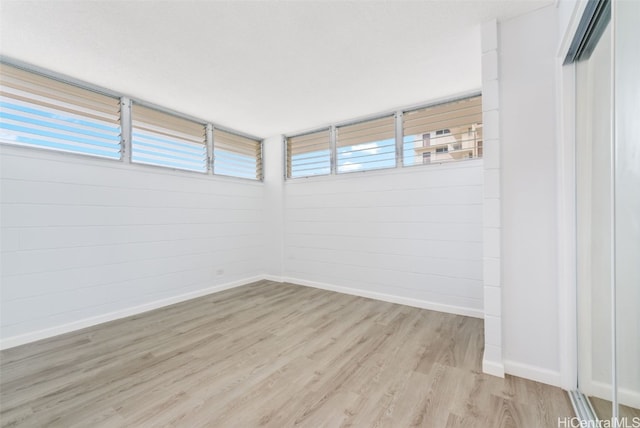 spare room featuring light wood-type flooring and plenty of natural light