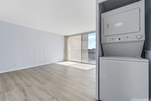 laundry room with stacked washing maching and dryer and light hardwood / wood-style floors