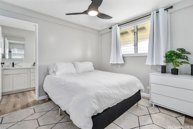 bedroom with ensuite bathroom, ceiling fan, sink, and light hardwood / wood-style flooring