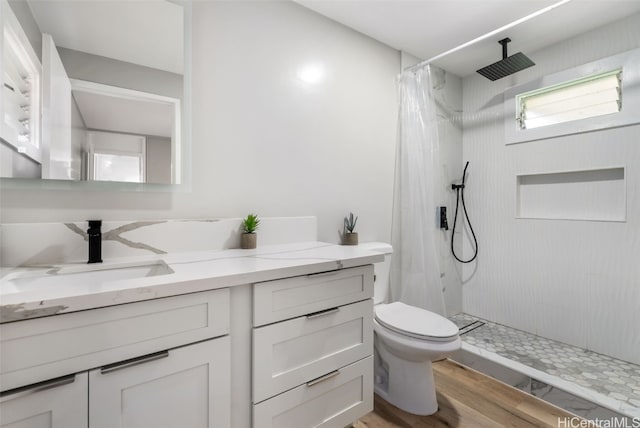 bathroom featuring toilet, vanity, hardwood / wood-style flooring, and curtained shower