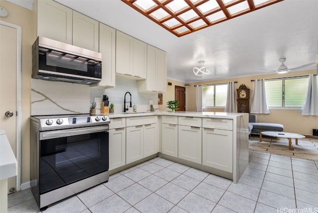 kitchen with kitchen peninsula, stainless steel appliances, light tile patterned floors, and tasteful backsplash