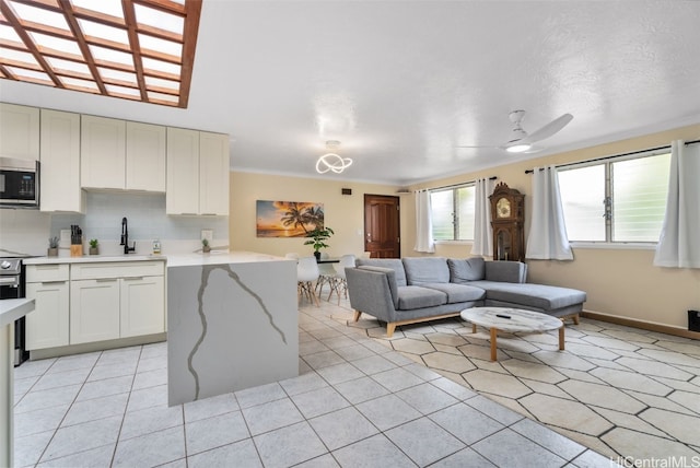 living room with ceiling fan, crown molding, and sink