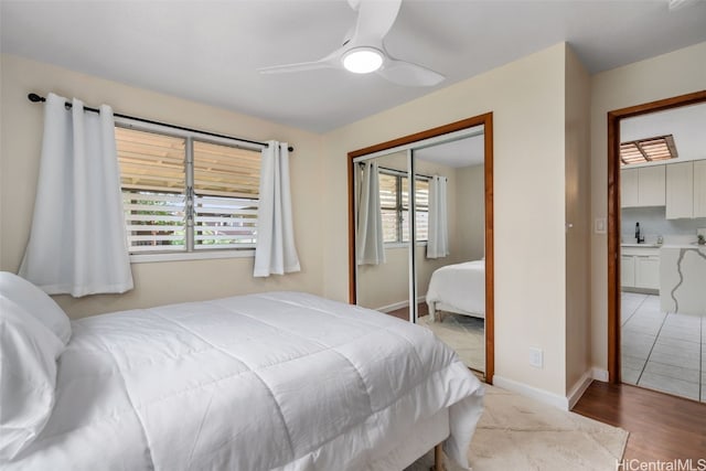 bedroom featuring light hardwood / wood-style flooring, ceiling fan, sink, and a closet