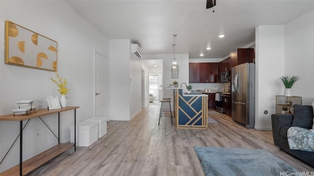 kitchen featuring hanging light fixtures, an island with sink, light hardwood / wood-style floors, a kitchen bar, and stainless steel appliances