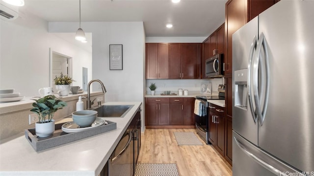 kitchen with sink, hanging light fixtures, stainless steel appliances, an AC wall unit, and light hardwood / wood-style floors