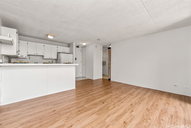 unfurnished living room featuring light wood-type flooring and a textured ceiling