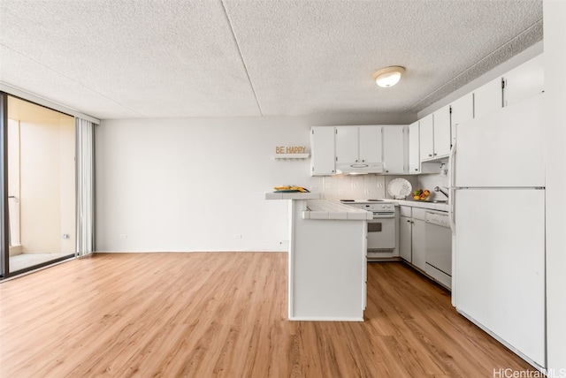 kitchen with white cabinets, white appliances, a textured ceiling, and light hardwood / wood-style flooring