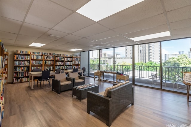 interior space with a drop ceiling, hardwood / wood-style floors, and a wall of windows