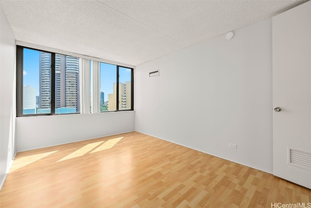 unfurnished room with hardwood / wood-style floors and a textured ceiling