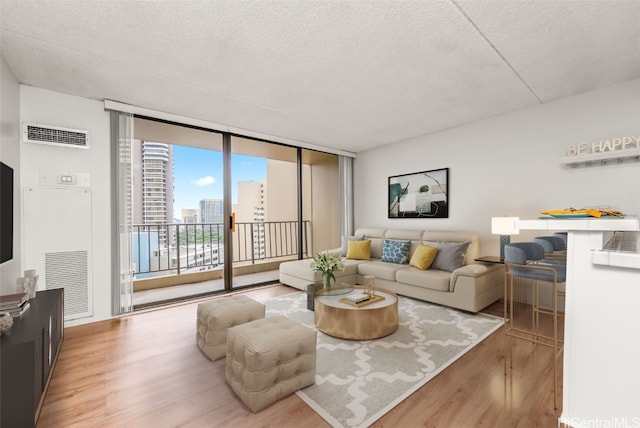 living room featuring a wall of windows, light hardwood / wood-style floors, and a textured ceiling