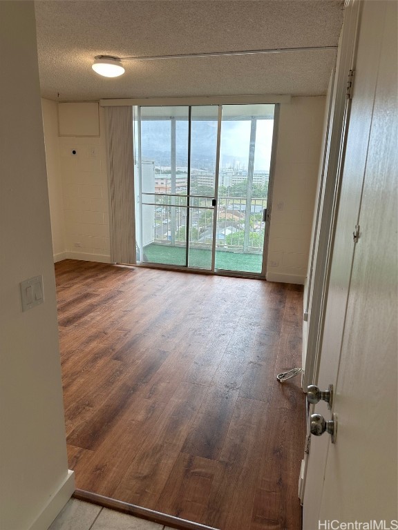 empty room with hardwood / wood-style floors and a textured ceiling