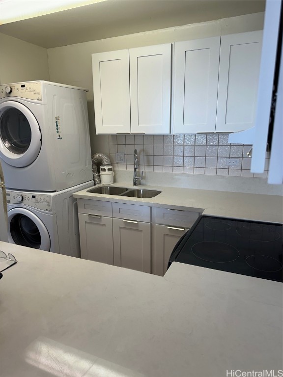 washroom featuring stacked washing maching and dryer and sink