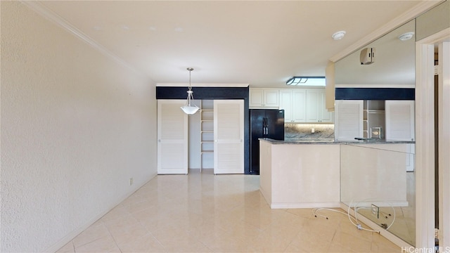 kitchen with crown molding, kitchen peninsula, black refrigerator, hanging light fixtures, and decorative backsplash