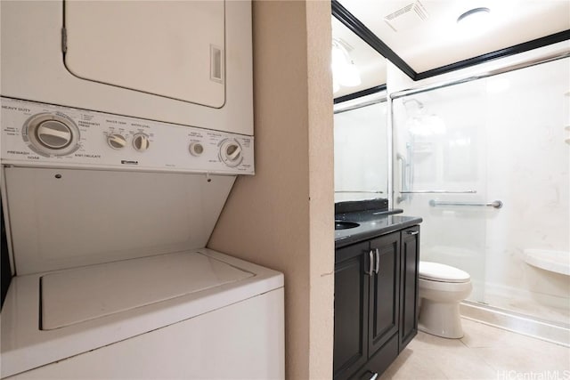 laundry area featuring stacked washer / dryer and light tile patterned flooring