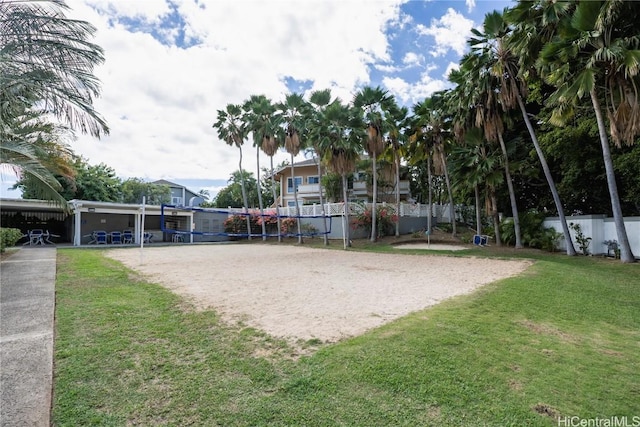 view of community with volleyball court, a lawn, and fence