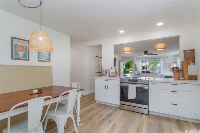 kitchen featuring stainless steel electric range, light wood-type flooring, hanging light fixtures, white cabinets, and kitchen peninsula