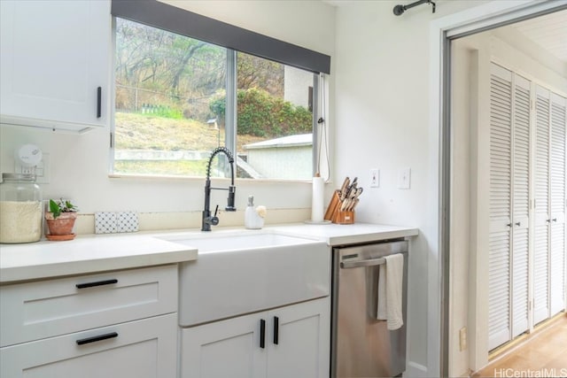 kitchen featuring white cabinetry, stainless steel dishwasher, sink, and light hardwood / wood-style flooring