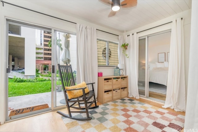 living area with ceiling fan, a wealth of natural light, wooden ceiling, and light hardwood / wood-style floors