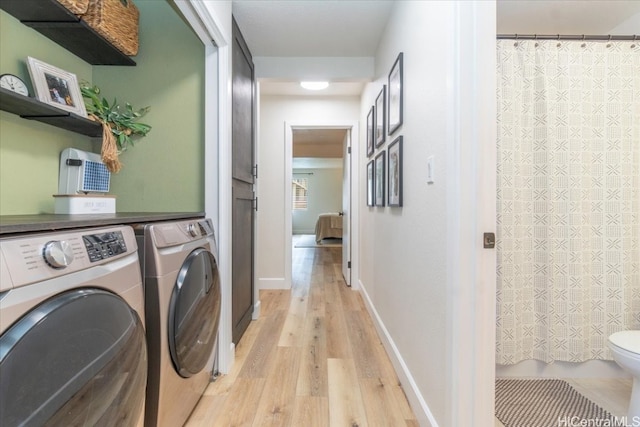 clothes washing area with separate washer and dryer and light wood-type flooring