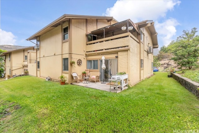 rear view of property featuring a balcony, a lawn, and a patio area