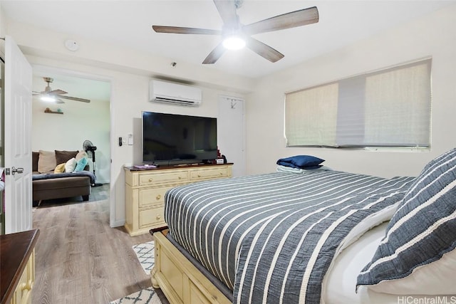 bedroom with ceiling fan, light hardwood / wood-style floors, and a wall mounted AC