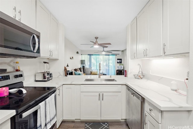 kitchen with sink, hardwood / wood-style flooring, white cabinetry, kitchen peninsula, and stainless steel appliances