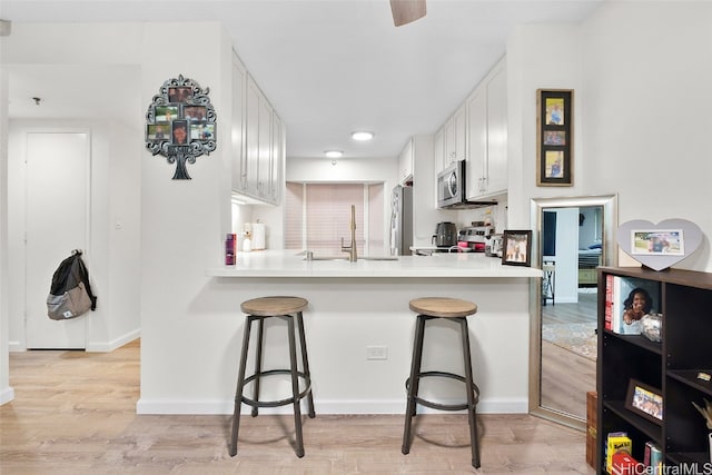 kitchen with a breakfast bar area, kitchen peninsula, and white cabinets