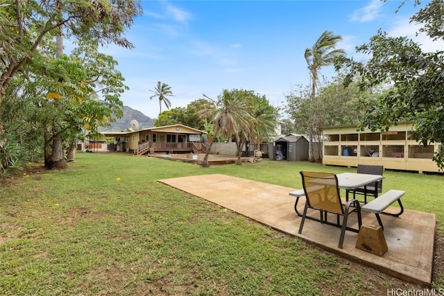 view of yard featuring a mountain view, a storage shed, and a patio