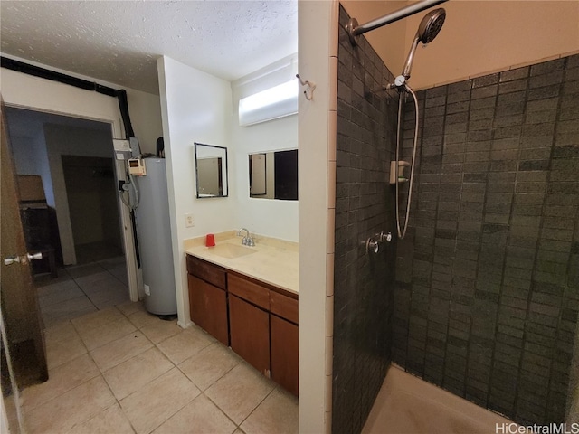 bathroom featuring a tile shower, vanity, a textured ceiling, water heater, and tile patterned flooring