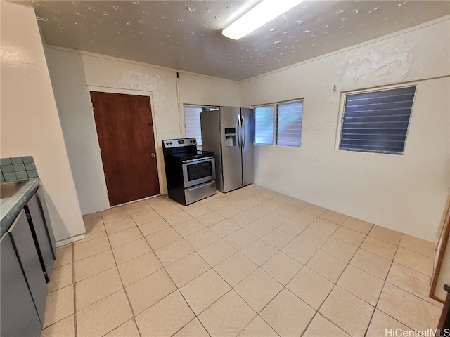 kitchen with light tile patterned floors, ornamental molding, and stainless steel appliances