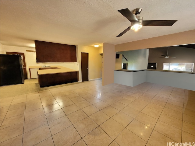 unfurnished living room with sink, a textured ceiling, light tile patterned floors, and ceiling fan