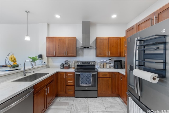 kitchen with pendant lighting, stainless steel appliances, sink, and wall chimney range hood