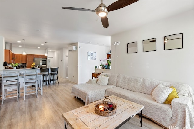 living room with a wall mounted AC, light hardwood / wood-style flooring, and ceiling fan