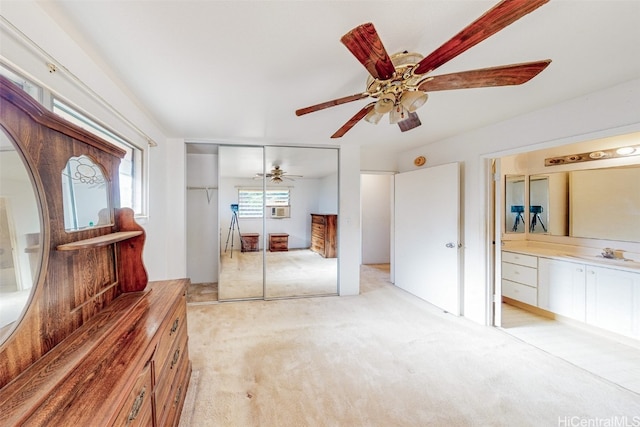 unfurnished bedroom with ceiling fan, sink, light carpet, and a closet