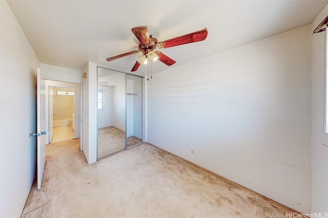 unfurnished bedroom with ceiling fan, light carpet, and a closet