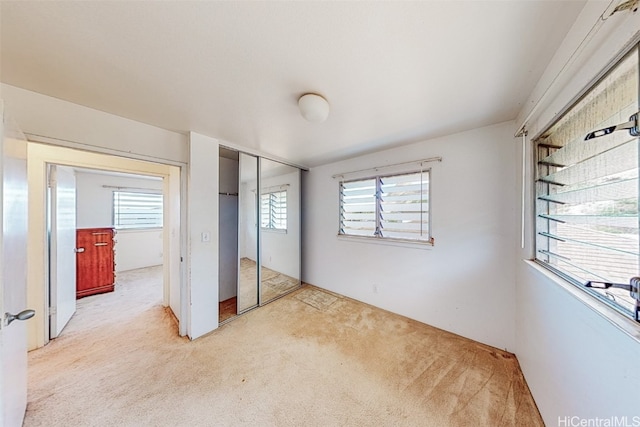 unfurnished bedroom with a closet, light carpet, and multiple windows