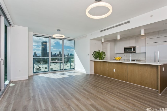 kitchen featuring light wood-type flooring, kitchen peninsula, floor to ceiling windows, and white cabinets