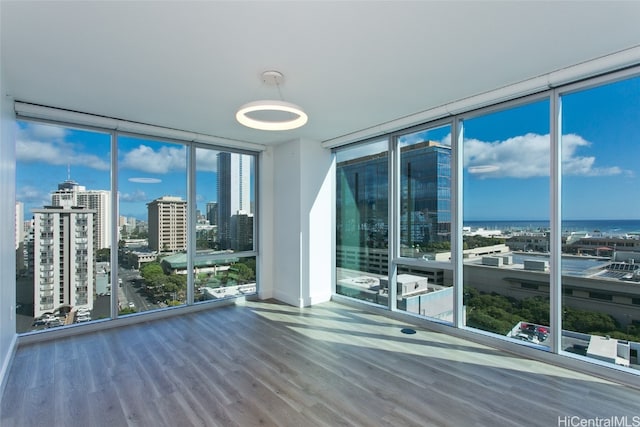 empty room featuring expansive windows, a water view, and hardwood / wood-style floors