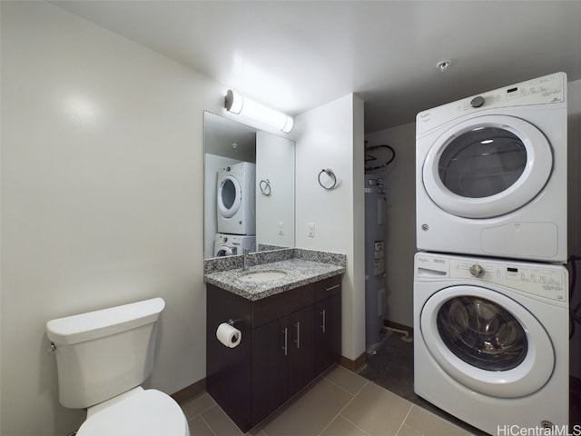 washroom with water heater, dark tile patterned flooring, sink, and stacked washer / dryer