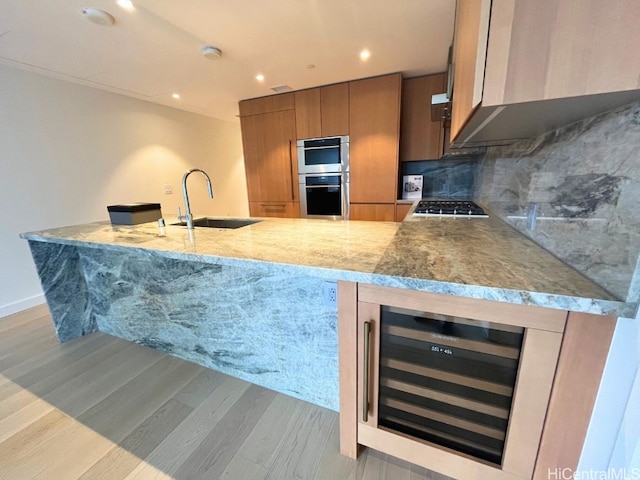 kitchen featuring decorative backsplash, appliances with stainless steel finishes, light wood-type flooring, beverage cooler, and sink