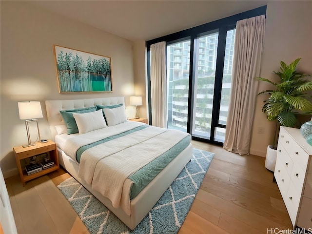 bedroom featuring access to outside, multiple windows, and light hardwood / wood-style flooring