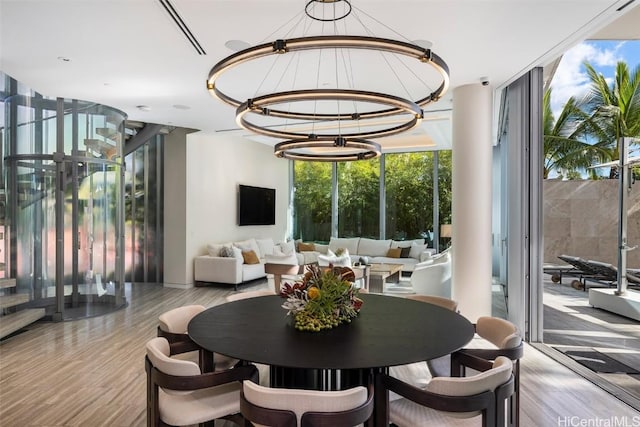 dining area with light hardwood / wood-style floors, an inviting chandelier, and a wall of windows