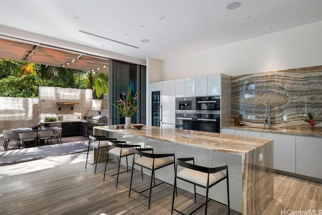 kitchen featuring white cabinets, a breakfast bar, light hardwood / wood-style flooring, and sink